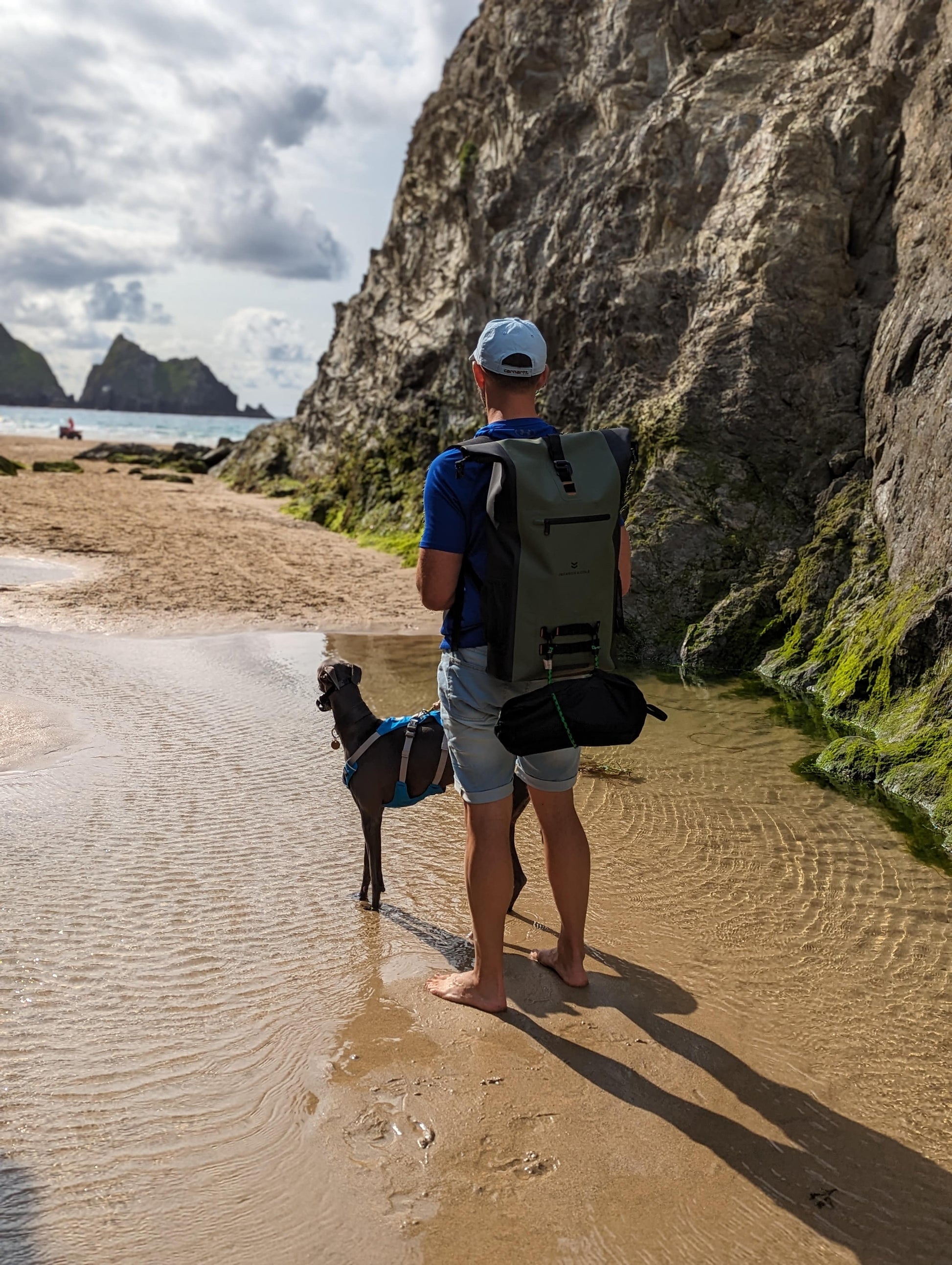 Man walking dog on beach wearing ancona backpack